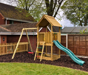 Holzspielturm für den Garten mit Rutsche und Schaukel in einem Hinterhof